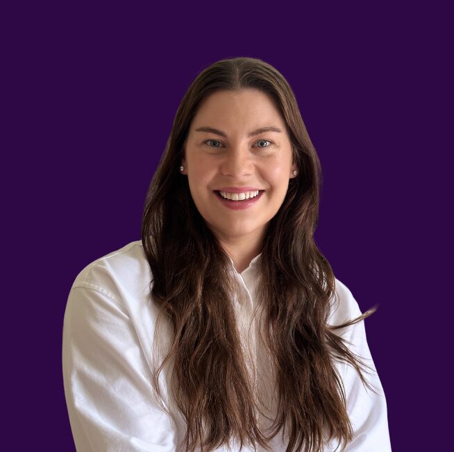 Jess Stolberg, a smiling woman with long brown hair, in a white shirt against a purple background