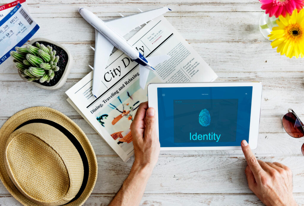 Travel flat lay with airplane, passport, and tablet showing "Identity